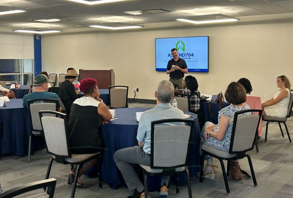 Entrepreneurs and business professionals gathered in a collaborative discussion inside a modern coworking space with natural light, plants, and active work areas.